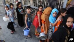 FILE - Iraqi children, most of them internally displaced persons, wait in line for free food being distributed at a mosque in Baghdad, Iraq, June 23, 2015.