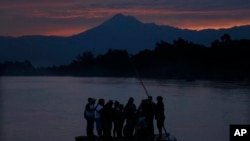 Central American migrants stand on a raft to cross the Suchiate River from Guatemala to Mexico, as the Tacana volcano stands tall near Ciudad Hidalgo, Mexico, early Monday, June 10, 2019. Mexican and U.S. officials reached an accord late Friday that…