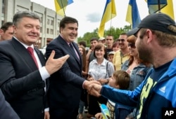 FILE - Seen during better times, Ukrainian President Petro Poroshenko, left, and then newly appointed Odesa region governor Mikheil Saakashvili, second left, shake hands with local residents, in Odesa, Ukraine, May 30, 2015.