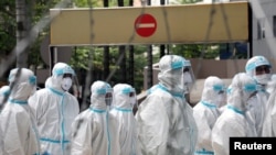 Police officers wearing protective suits gather outside an apartment under enhanced lockdown to pick up illegal immigrants, due to the outbreak of the coronavirus disease (COVID-19), in Kuala Lumpur, Malaysia, May 1, 2020. 