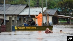 Agentes de policía revisan una casa mientras habitantes vadean una calle inundada por tormentas derivadas de un ciclón en Passo Fundo, en el estado de Rio Grande do Sul, Brasil, el 4 de septiembre de 2023.