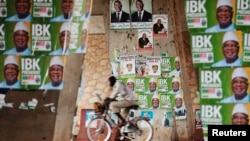 A man rides a bicycle past electoral campaign posters in Bamako August 9, 2013.