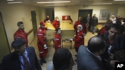 Syrian Red Crescent workers stand with the coffins of American journalist Marie Colvin, left, and French photojournalist Remi Ochlik at Assad hospital in Damascus, Syria, Saturday, March 3, 2012. 