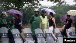 Riot police stand by the side of the road at the entrance of Yuhang town after a night of riots, west of Hangzhou, Zhejiang province, May 11, 2014. 