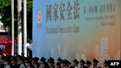 资料照：香港警察举行升旗仪式与他们背后的国安法宣传牌。（2020年7月1日）