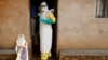Health care workers enter a house where a baby suspected of dying of Ebola is, during the baby's funeral in Beni, North Kivu province, Democratic Republic of the Congo, Dec. 18, 2018. 