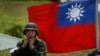 资料照：台湾旗帜前一名士兵整理自己的头盔。 