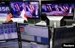 FILE - An employee of a foreign exchange trading company looks at monitors showing U.S. President elect Donald Trump speaking on TV news in Tokyo, Japan, Nov. 9, 2016.