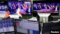 An employee of a foreign exchange trading company looks at monitors showing U.S. President elect Donald Trump speaking on TV news in Tokyo, Japan, Nov. 9, 2016.