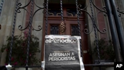 ARCHIVO - Una copia de la portada de elPeriódico, que reza "Periodistas asesinados", cuelga en una puerta principal de la Casa Presidencial durante una protesta en marzo de 2015.