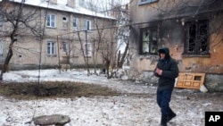 A man walks past a mortar impact site outside a damaged building in Donetsk, eastern Ukraine, Dec. 9, 2014.