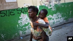 A boy suffering cholera symptoms is carried by a relative to St. Catherine hospital in Cite Soleil slum in Port-au-Prince, 18 Nov 2010