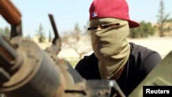 A masked member of Libyan internationally recognized pro-government forces is seen in a military vehicle on the outskirts of Tripoli, Libya, April 10, 2019.