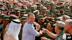 President George H.W. Bush is greeted by Saudi troops and others as he arrives in Dhahran, Saudi Arabia, for a Thanksgiving visit, Nov. 22, 1990. Bush died at the age of 94 on Friday, Nov. 30, 2018, about eight months after the death of his wife, Barbara Bush.