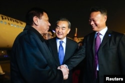 President of the Philippines Rodrigo Duterte (L) shakes hands with Chinese ambassador to the Philippines Zhao Jianhua (R), as Chinese Foreign Minister Wang Yi (C) looks on, at airport in Beijing, Oct. 18, 2016.