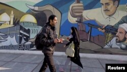 Iranians walk past a revolutionary mural in Tehran, Iran, January 17, 2016.