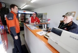 Kevin Beyer, general manager of Farmers, a century-old phone company, talks with Morrie, center, and Al Schacherer at the auto shop they run in Dawson, Minn., Nov. 19, 2013. Farmers laid 600 miles of fiber cable in 2011 with the help of $9.6 million in stimulus grants and loans.