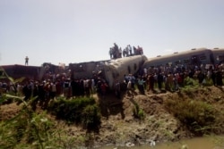 People inspect the damage after two trains collided near the city of Sohag, Egypt, March 26, 2021.