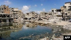 Sewage water from collapsed underground pipes covers an area by destroyed buildings in Khan Yunis in the southern Gaza Strip on July 8, 2024 amid the ongoing conflict in the Palestinian territory between Israel and Hamas.