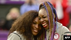 Petenis Serena Williams (kiri) dan kakaknya Venus Williams setelah meraih medali emas nomor ganda putri dalam Olimpiade 2012.