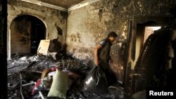 A worker carries luggage from a house that burnt after an air strike by a Saudi-led coalition struck a nearby missile base, in Yemen's capital Sanaa, April 23, 2015.