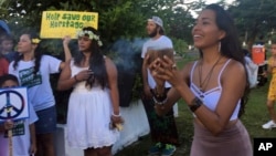 Eva Aguon Cruz, 30, holds a cup with burned flower as a ritual to call for protections from the spirits as about a hundred people gather at Chief Kepuha Park in Hagatna, Guam, for a rally for peace, Aug. 14, 2017. The threatened missile attack by North Korea on Guam has prompted calls for peace from the island's indigenous people, who are weary of yet another conflict after enduring centuries of hostilities. 