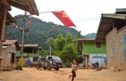 A girl runs across the street in Khokkham, one of six villages in northern Laos to be entirely flooded by the construction of the Luang Prabang dam. (Zsombor Peter/VOA)