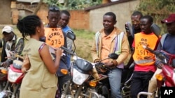 Martine Milonde, left, a Congolese community mobilizer who works with the aid group World Vision in Beni, eastern Congo, which became the epicenter of the Ebola outbreak, engages the public about coronavirus prevention, April 10, 2020.
