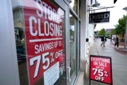 FILE - Pedestrians walk past a business storefront with closing and sale signs in Dedham, Mass., Sept. 2, 2020.