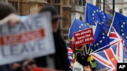 Pro and anti Brexit demonstrators wave their placards and flags outside the Houses of Parliament in London, Dec. 18, 2018.