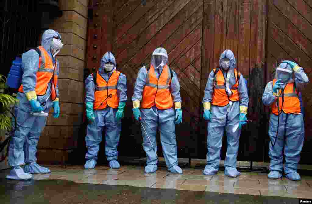 Municipal workers wearing personal protective equipment wait to enter Bollywood actor Amitabh Bachchan's residence for sanitization after he and his son, actor Abhishek Bachchan, tested positive for the coronavirus disease (CIVID-19), in Mumbai, India.