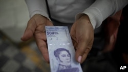 Una mujer muestra un nuevo billete de 500.000 bolívares después de retirarlo de un banco en Caracas, Venezuela. Marzo 16, 2021.