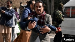 A man carries a boy as he walks away from the Bethel Memorial Methodist Church in Quetta, Pakistan, after gunmen attacked, Dec. 17, 2017.