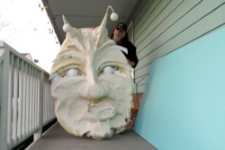 FILE - Thom Karamus shows his papier-mâché head of the hookah-smoking caterpillar from "Alice in Wonderland," Jan. 14, 2021, in New Orleans. All around the city, thousands of houses are being decorated as floats for Mardi Gras.