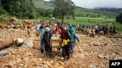 FILE - Men carry a coffin on along a makeshift path on the river in Ngangu township Chimanimani, Manicaland province, eastern Zimbabwe, after the area was hit by Cyclone Idai.