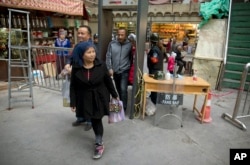 FILE - Residents past through one of the many security check points in Kashgar in western China's Xinjiang region, Nov. 4, 2017.