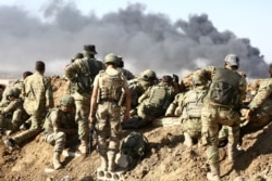 FILE - Turkish troops and Turkish-backed Syrian rebels gather outside the border town of Ras al-Ayn on Oct. 12, 2019, during their assault on Kurdish-held border towns in northeastern Syria.