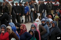 Syrians line up for food at a distribution center in the northwestern city of Afrin, Syria, during a Turkish government-organized media tour into northern Syria, March 24, 2018.