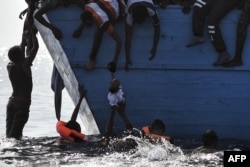 FILE - Migrants try to pull a child out of the water as they wait to be rescued by members of Proactiva Open Arms NGO in the Mediterranean sea, some 12 nautical miles north of Libya, Oct. 4, 2016.