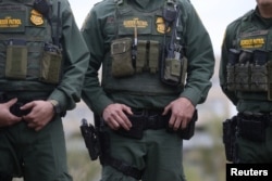U.S. Customs and Border Patrol agents watch as President Donald Trump visits the banks of the Rio Grande River in Mission, Texas, Jan. 10, 2019.