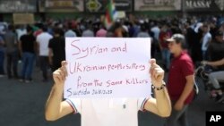 A man holds a placard during a protest in the southern city of Sweida, Syria, on Aug 26, 2023. Insurgents in northwest Syria attacked an army position on the same day, killing and wounding more than 30 troops, activists said. (Suwayda24 via AP)