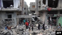 Warga Palestina memeriksa kerusakan dan puing-puing sehari setelah operasi Pasukan Khusus Israel di kamp Nuseirat, di Jalur Gaza tengah pada 9 Juni 2024, di tengah konflik antara Israel dan kelompok militan Hamas Palestina.