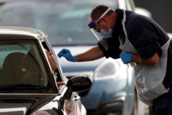 FILE - A passenger in a car receives a novel coronavirus test at a drive-in COVID-19 testing facility set up at the Chessington World of Adventures Resort, in Chessington, southwest of London, Oct. 20, 2020.