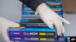 FILE - Youngstown City Health Department worker Faith Terreri grabs two at-home COVID-19 test kits to be handed out during a distribution event, Dec. 30, 2021, in Youngstown, Ohio. 