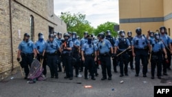 FILE - Minneapolis police officers stand in a line facing protesters demonstrating against the death of George Floyd, outside the 3rd Police Precinct in Minneapolis, Minnesota, May 27, 2020. 
