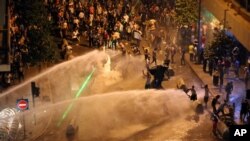Lebanese activists shout anti-government slogans as they are sprayed by riot police using water cannons during a protest against the ongoing trash crisis, in downtown Beirut, Lebanon, Sunday, Aug. 23, 2015.