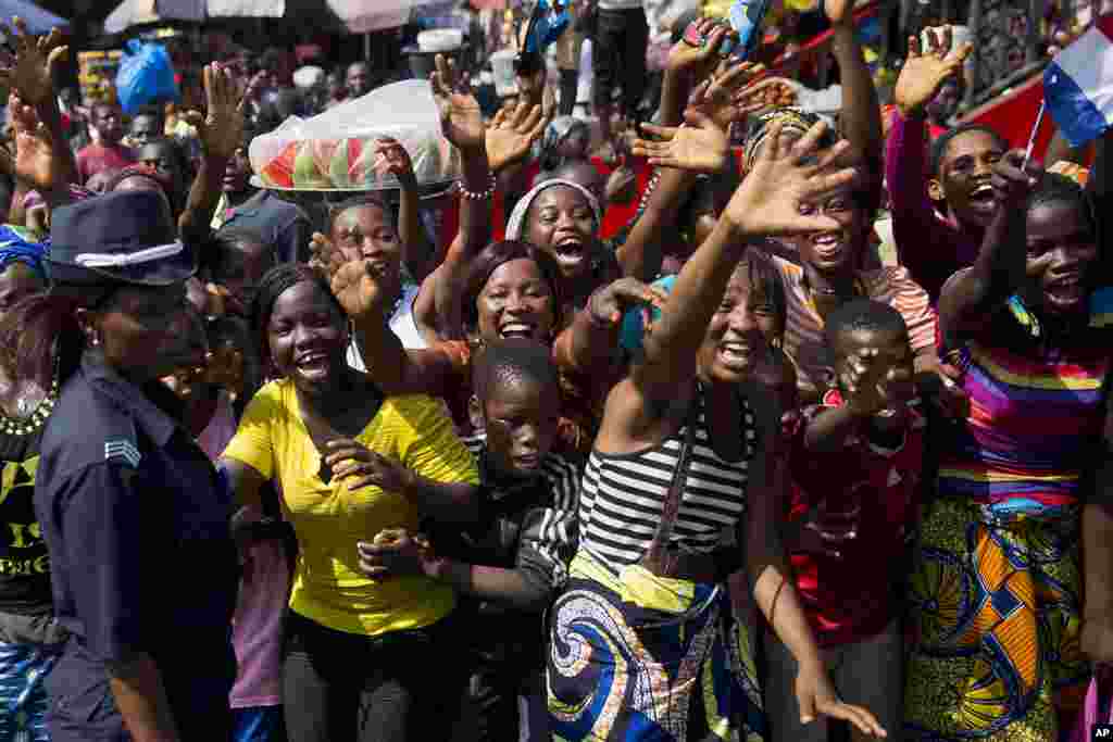 People welcome the motorcade carrying French President Francois Hollande and his Guinean counterpart Alpha Conde in Conakry, Guinea, Friday Nov. 28, 2014.