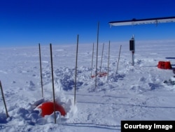 Seismic installation near McMurdo Field Station shows solar panel, the top of the box peeking out, and the top of a dome that covers the seismometer. (Credit: Paul Carpenter)