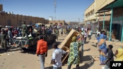 Malian troops try to dissuade the crowd from looting shops in Timbuktu, Jan. 29, 2013. Hundreds of Malians looted Arab-owned shops Tuesday in Mali's fabled Timbuktu, newly freed from Islamists.