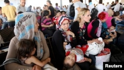 FILE - Syrian refugees wait to cross the border into the autonomous Kurdish region of northern Iraq. 